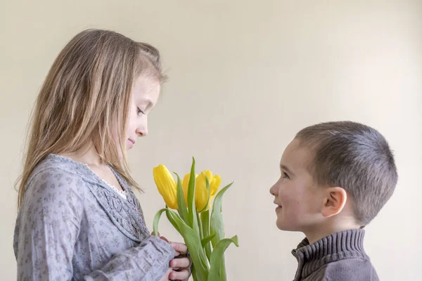 the little gentleman gives the girl a bunch of flowers. The little boy gives yellow tulip