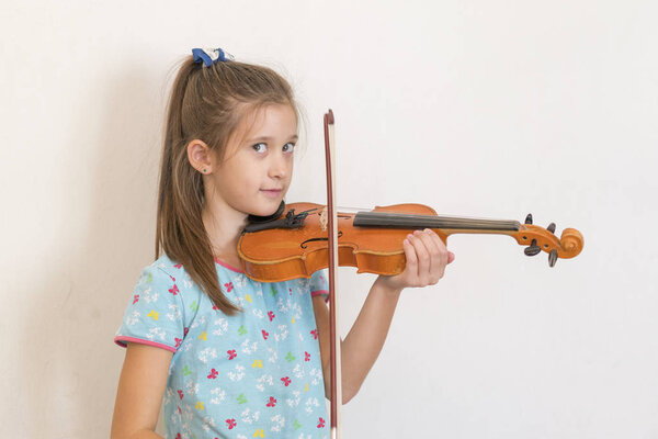 Cute pupil playing violin in classroom at the elementary school. Girl playing the violin.