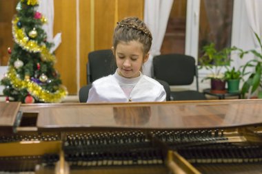 Güzel elbiseli bir kız üzerinde kahverengi bir kuyruklu piyano çalış.