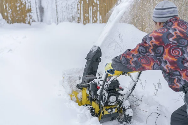 A man cleans snow from sidewalks with snowblower. A snow thrower is the best assistant for snow removal in the winter. Snow Thrower outdoor — Stock Photo, Image