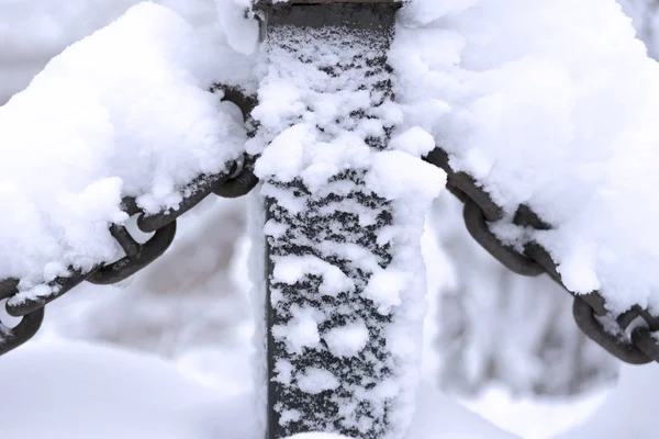 Schneebedeckte Metallkette auf dem weißen, schneebedeckten Hintergrund — Stockfoto