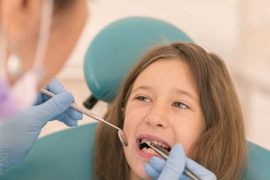 Açık ağız, diş hekimi ile genç çocuğun makro yakın çekim. Diş check-up dişçi ofisinde. Dişçi kız diş diş hekimleri sandalyede incelenmesi