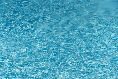 Mavi su yüzme havuzu arka planda. Güneş yansıması ile yüzme havuzunda su dalgalanma. Mavi yüzme havuzu su ayrıntı et kalınlığı ile yivli.