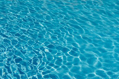 Mavi su yüzme havuzu arka planda. Güneş yansıması ile yüzme havuzunda su dalgalanma. Mavi yüzme havuzu su ayrıntı et kalınlığı ile yivli.