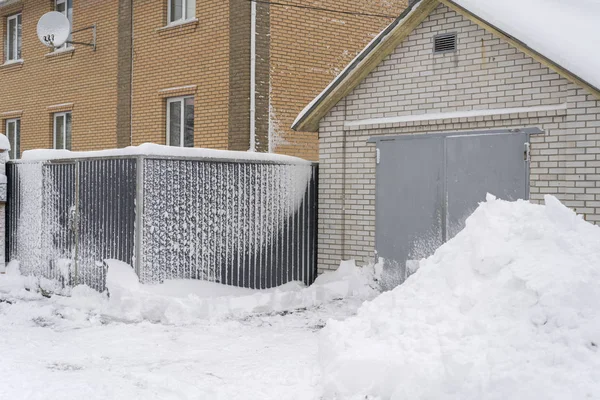 Snow-covered gate and trick. snow sweeps. The concept of a snowy winter. Snow blocked the entrance. Snow-covered iron gates. winter wrought fence gates.