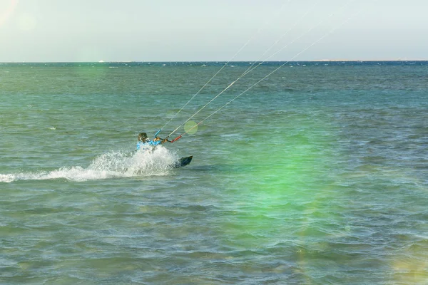 Kitesurfing Kiteboarding fotos de ação homem entre ondas vai rapidamente. Um kite surfista monta as ondas. iluminação da lente. tonificado — Fotografia de Stock