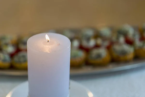 Burning white candle on a blurred background