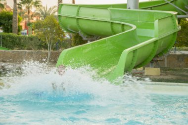 Çocuk, aquapark zaman harcama yaparken eğleniyor. Çok sayıda su sıçramalarına yapım su kaydırağı kayıyor
