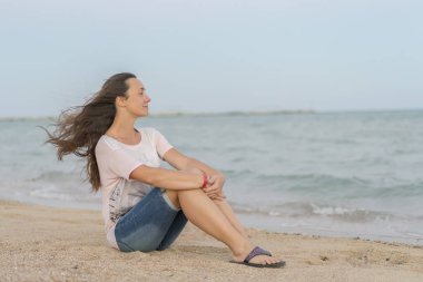 Güzel kız sahilde oturuyor. Orta denize sıfır plaj, istirahat kadın yaşlı. Sahilde uzun akan saçlı Genç, güzel kadın.