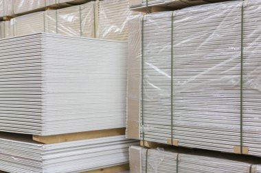 Alçıtaşı alçıtaşı pakette. Alçıtaşı yığını inşaata hazırlanıyor. İnşaat dükkanında alçıpanlı palet. İnşaat malzemeleri. Alçıpan deposu