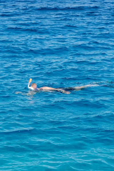 man with snorkel mask tuba and snorkel in sea. Snorkeling, swimming, vacation. Tourists are engaged in snorkeling in the open sea. Holidays in the seaside resort. vertical photo