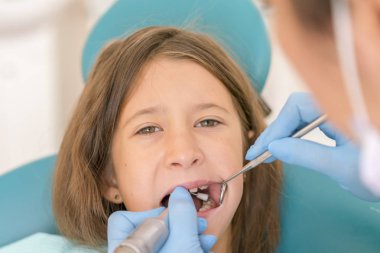 Açık ağız, diş hekimi ile genç çocuğun makro yakın çekim. Diş check-up dişçi ofisinde. Dişçi kız diş diş hekimleri sandalyede incelenmesi. dikey fotoğraf.