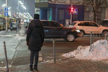 Yaya trafik ışıkları sırasında karşıdan karşıya için bekleyen kız gece şehirde kırmızıdır