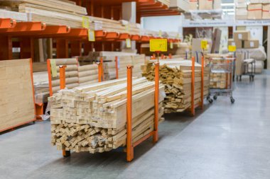 Kereste Amerika'da büyük donanım deposunun içinde raflarda yeni ahşap çubukları yığını. Taze değirmen raf ya da Ahşap ahşap Kafesli döşeme sepeti ve manuel forklift ambarı ile kesme
