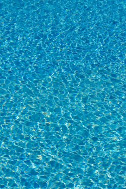 Mavi su yüzme havuzu arka planda. Güneş yansıması ile yüzme havuzunda su dalgalanma. Mavi yüzme havuzu su ayrıntı et kalınlığı ile yivli. dikey fotoğraf