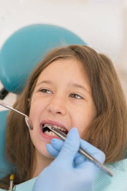 Açık ağız, diş hekimi ile genç çocuğun makro yakın çekim. Diş check-up dişçi ofisinde. Dişçi kız diş diş hekimleri sandalyede incelenmesi. dikey fotoğraf