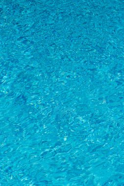 Mavi su yüzme havuzu arka planda. Güneş yansıması ile yüzme havuzunda su dalgalanma. Mavi yüzme havuzu su ayrıntı et kalınlığı ile yivli. dikey fotoğraf