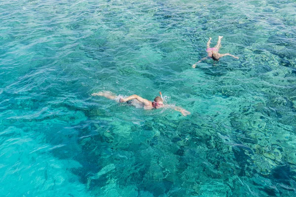 Man and women snorkeling in tropical water on vacation. Woman swimming in blue sea. Snorkeling girl in full-face snorkeling mask. People in flippers and masks in the clear sea