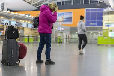 Onu uçuş kontrol bilgi tahtaya arıyorsunuz genç kadınla el bagajı Uluslararası Havaalanı terminal. havaalanında bir çanta ile kız
