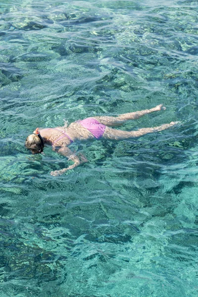 Junges Mädchen schnorchelt im Urlaub im tropischen Wasser. Frau schwimmt im blauen Meer. Schnorchelmädchen in Ganzgesicht-Schnorchelmaske. vertikales Foto. — Stockfoto