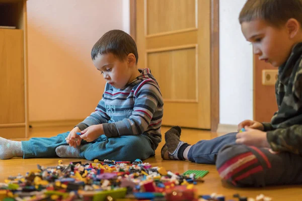 Двое Детей Играли Кучей Разноцветных Пластиковых Блоков Сидели Полу Помещении — стоковое фото