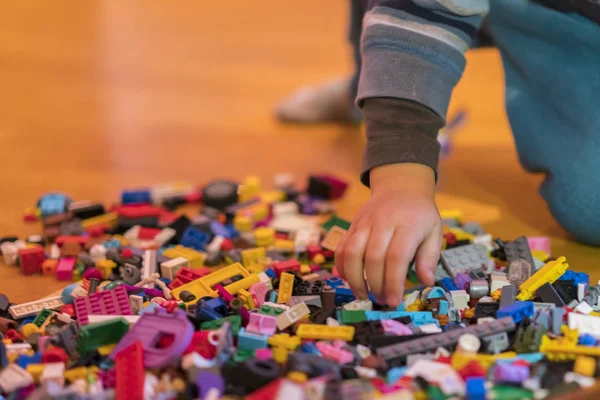 Yerdeki renkli plastik tuğla kapatın. Erken öğrenme. Çocuk yerdeki plastik Oluşturucu. Küçük bir Oluşturucu çocuk el oynayın