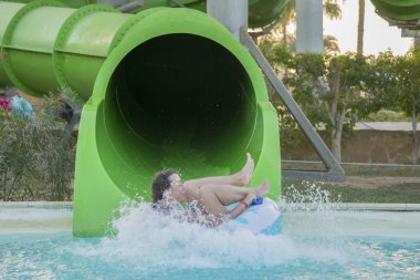 Güzel kız bir su kaydırağı sürme. mutlu kadın kauçuk halka turuncu slayt aqua park tarafından aşağı gidiyor. Yaz tatili. Hafta sonu resort