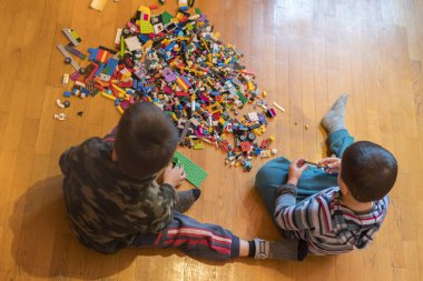 İki çocuk bir yere kapalı oturma renkli plastik blok Oluşturucu dolu oyun. İki küçük kardeş Oluşturucu oynamak. İletişim ve dostluk. Üstten görünüm
