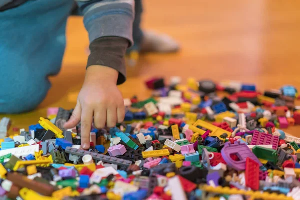 Yerdeki renkli plastik tuğla kapatın. Erken öğrenme. Çocuk yerdeki plastik Oluşturucu. Çocuk el küçük bir Oluşturucu oynayın. dikey fotoğraf