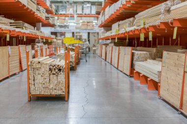 Kereste Amerika'da büyük donanım deposunun içinde raflarda yeni ahşap çubukları yığını. Taze değirmen raf ya da Ahşap ahşap Kafesli döşeme sepeti ve manuel forklift ambarı ile kesme
