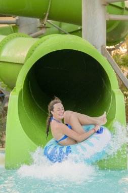 kadın su kaydırağı. mutlu kadın kauçuk halka turuncu slayt aqua park tarafından aşağı gidiyor. Yaz tatili. Hafta sonu resort. dikey fotoğraf.