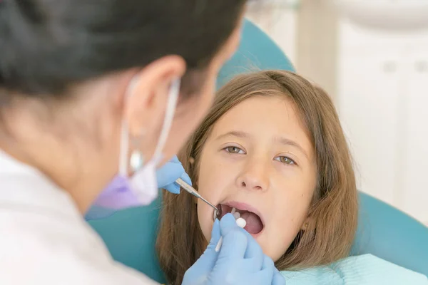 Little girl at the reception in the dentist\'s office. little girl sitting in a chair near a dentist after dental treatment. Little girl sitts in the dentist\'s office