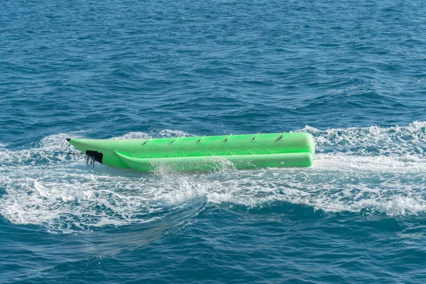 empty inflatable green banana boat in the sea. Banana Boat for fun on water surface in summer day - banana boat at the sea