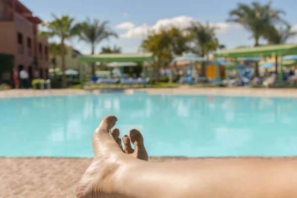 漂亮的晒黑的腿女性腿特写镜头 背景上有游泳池 美丽的女性腿在游泳池的背景 在酒店休息的概念 — 图库照片