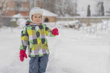 küçük oğlan havai fişekleri ile sokakta duruyor. Maytap ile mutlu bebek