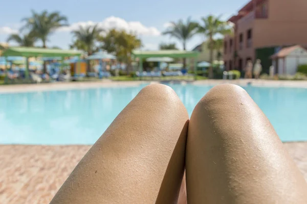 beautiful legs in the girl against the background of water. Beautiful long slender female legs of a girl with knees and hips against the backdrop of a pool with water