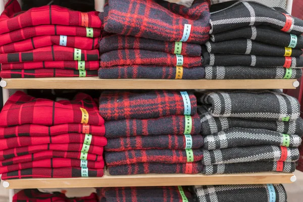 Neatly folded clothes. Rack of clothes with warm. Wooden cabinet with a stack of sweaters. Coloured clothing. Neat stacks of folded clothing on the shop shelves.