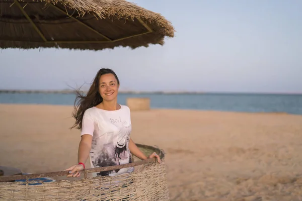 woman on the beach taking deep breath enjoying fresh air freedom. Happy young woman enjoying sea breeze at sunset. Girl on the beach with pleasant wind on her face. vertical photo