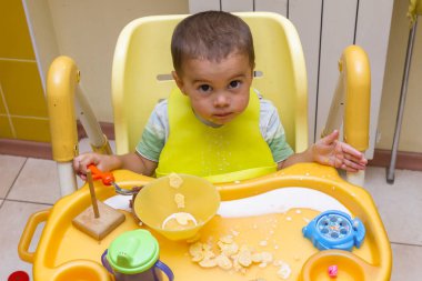 Küçük çocuk çocuk mutfakta çocuk masasında yemeye öğrenir. Komik bebek yiyor. Küçük bebek ile bir kaşık çorba plaka yiyor. Gıdalar koyarak bir çocuk sandalyede oturuyor.