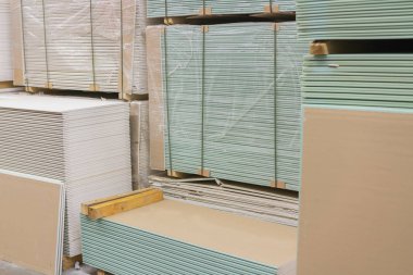 Alçıtaşı alçıtaşı pakette. Alçıtaşı yığını inşaata hazırlanıyor. İnşaat dükkanında alçıpanlı palet. İnşaat malzemeleri. Alçıpan deposu.