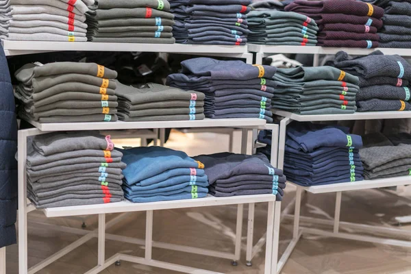 Neat stacks of folded clothing on the shop shelves. Color folding shirt In a neatly organized clothing store