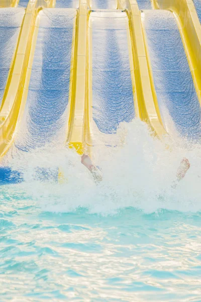 女の子スライディングの水の公園 ウォーターパークの水スライドの滑り降りる女性 垂直写真 — ストック写真