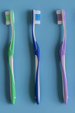 Mavi arka plan üzerinde diş fırçaları. Düz renkli arka plan üzerinde el ile diş fırçası ile kompozisyon yatıyordu, yakın çekim. kopya alanı. dikey fotoğraf