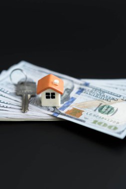 Küçük Model ev ve yeni tasarlanmış Amerikan tuşları Yüz dolarlık banknotlar. Satın alınan evin anahtarları. Siyah bir arka plan şirketten indirimli kopyası. dikey fotoğraf