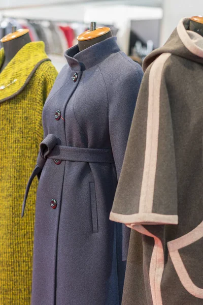 Women's coat in the store. Spring women's coats hanging on a rack in a women's clothing store. ertical photo