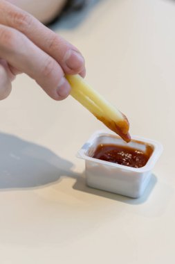 Domates soslu patates kızartması daldırma el close-up. El taze patates kızartması ile domates sosu daldırma. Dikey atış. kopya alanı