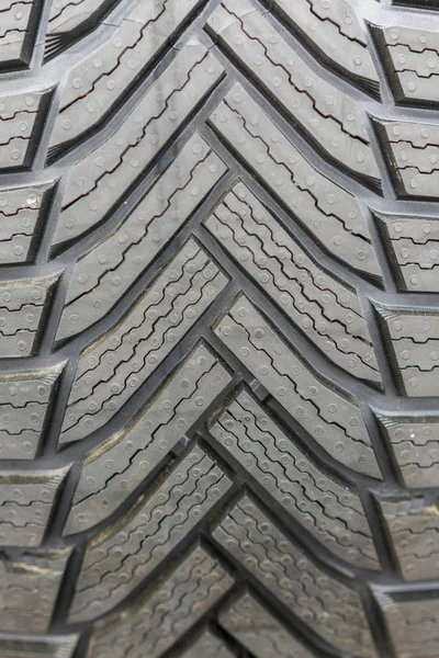 Close-up winter tire tread. Textured tire tread. Part of brand new modern winter car tire. vertical photo