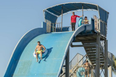 Hurghada, Mısır. 19 Kasım 2018 adam kızla su aşağı kaydırın. Kız tepeden aşağı gitmeye korkuyor. Çift su parkında.