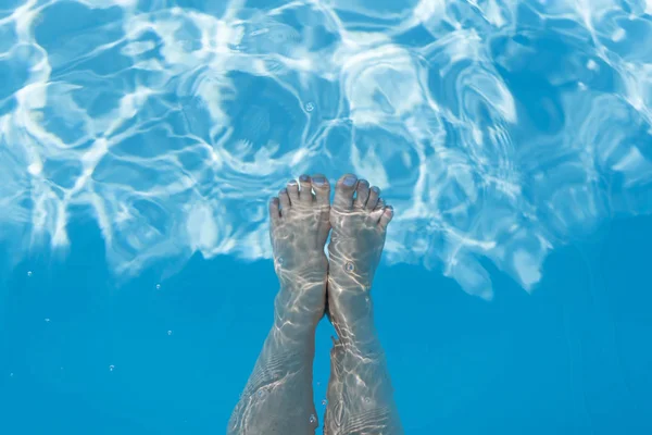 美丽的女性腿在游泳池的水特写镜头 池子里的腿暑假假期 — 图库照片
