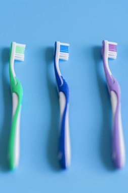 Mavi arka plan üzerinde diş fırçaları. Düz renkli arka plan üzerinde el ile diş fırçası ile kompozisyon yatıyordu, yakın çekim. kopya alanı. dikey fotoğraf.